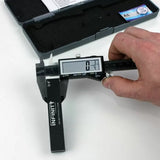 Digital caliper measuring woodworking router bit diameter on white surface