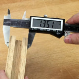 Digital caliper measuring a wooden dado joint on a workbench