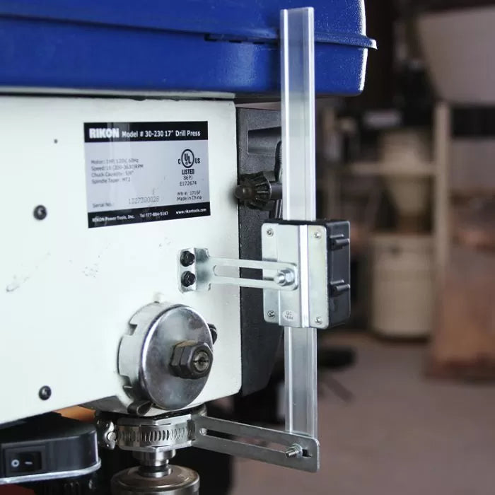 Drill press depth stop attachment on side of bench-top drill press in workshop