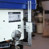 Drill press depth stop attachment on side of bench-top drill press in workshop