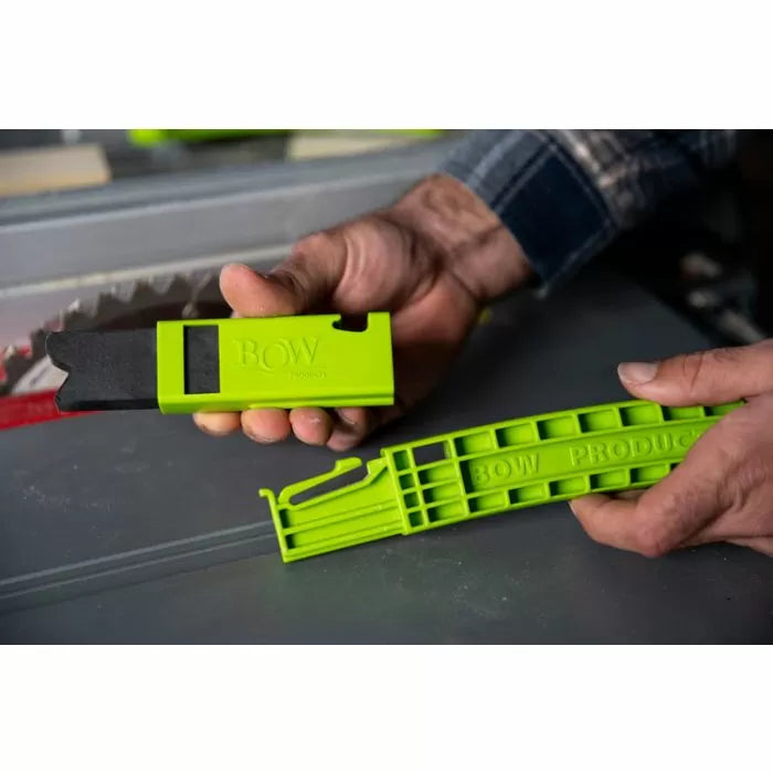 Person holding green bow push stick and tool near a table saw blade for woodworking safety