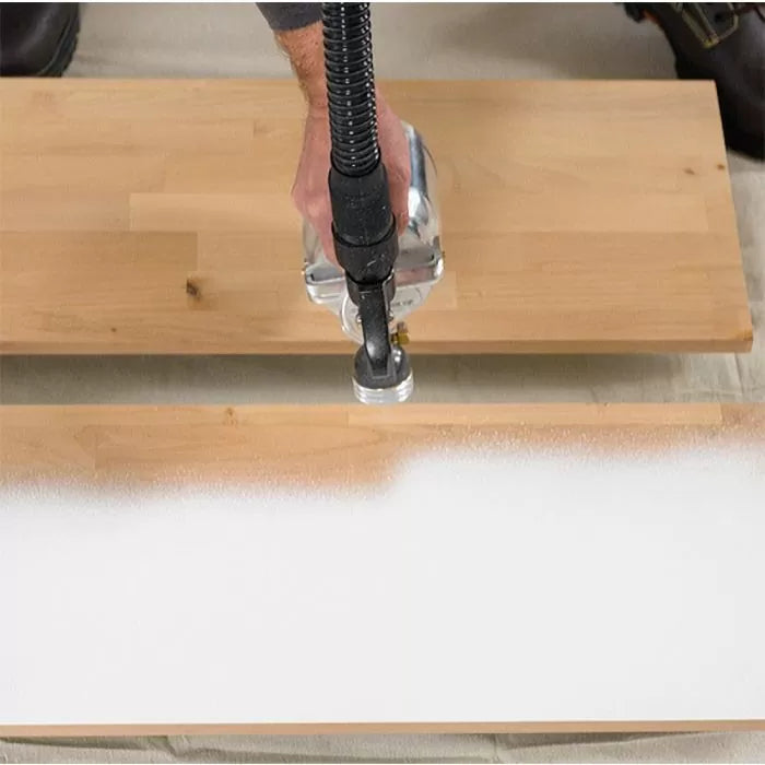 Hand using a paint sprayer to coat a wooden board for woodworking projects