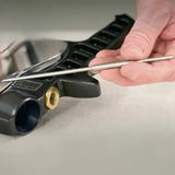 Hand holding spray gun needle beside paint sprayer part on workbench