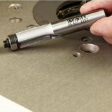 Hand holding straight router bit above metal router table, woodworking tool close-up