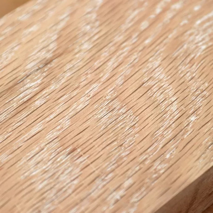 White grain filler applied to unfinished wood surface, highlighting wood grain texture.