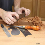Woodworker using hand scraper on wood with cabinet scraper set and burnisher on workbench