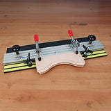 Woodworking jig with adjustable clamps holding curved wooden pieces on a workbench