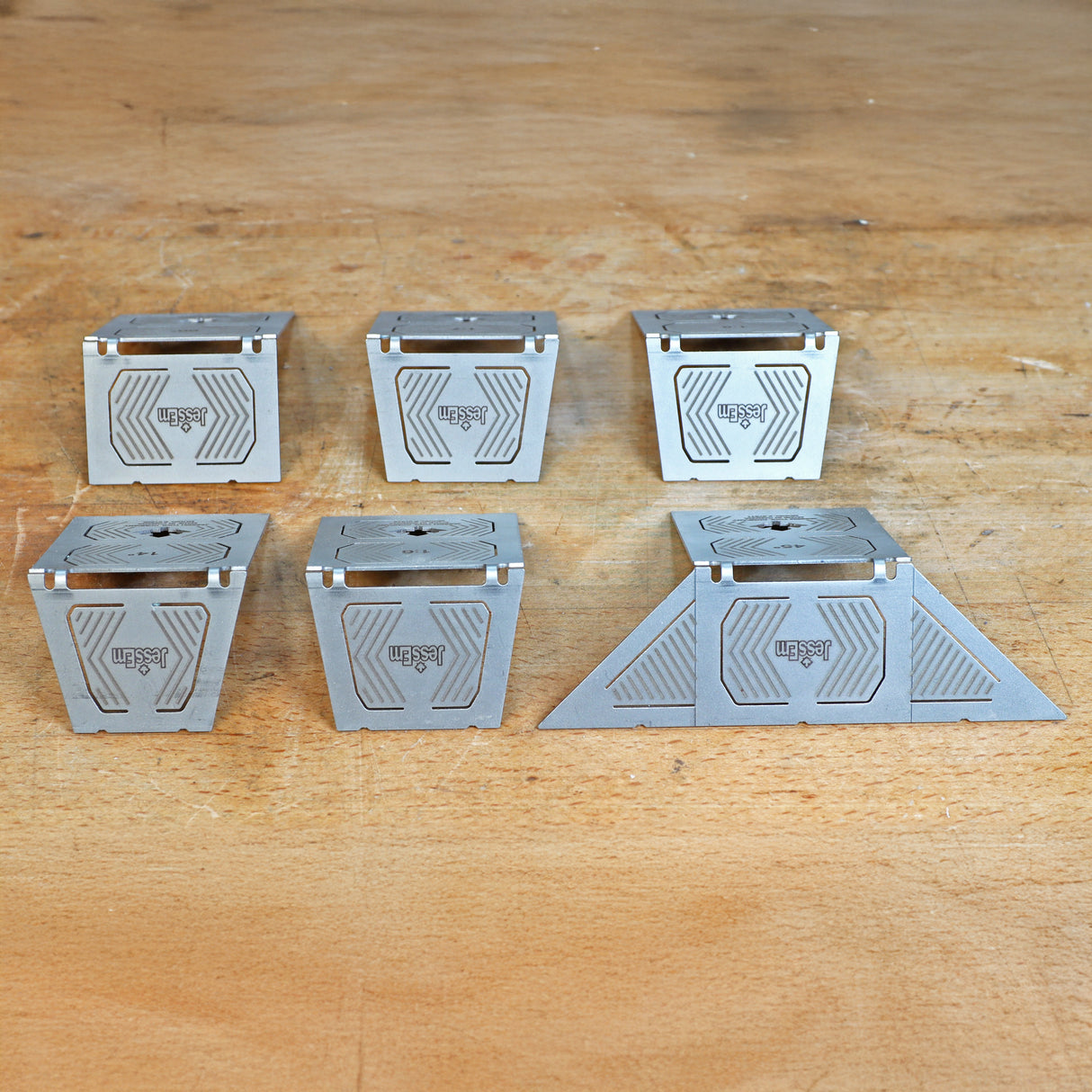 Set of six metal woodworking jigs with geometric patterns on a wooden workbench
