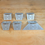 Set of six metal woodworking jigs with geometric patterns on a wooden workbench