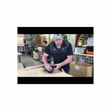 Man demonstrating a handheld woodworking tool on a workbench in a workshop