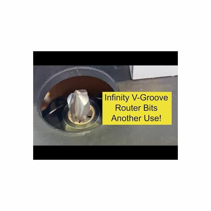 Close-up of V-groove router bit installed in router table with yellow text overlay.
