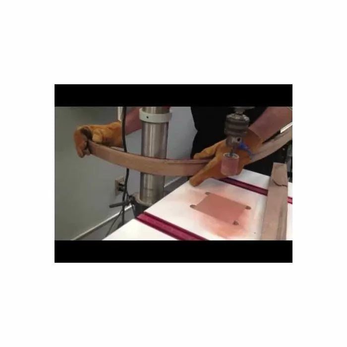 Woodworker using spindle sander to shape curved wood piece, wearing safety gloves.