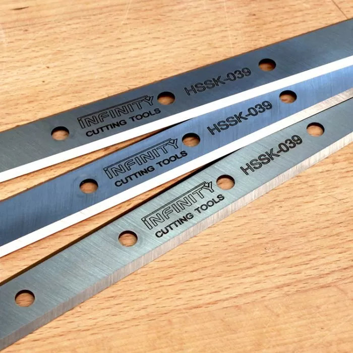 Steel planer knives with mounting holes on a wood surface, labeled HSSK-039.