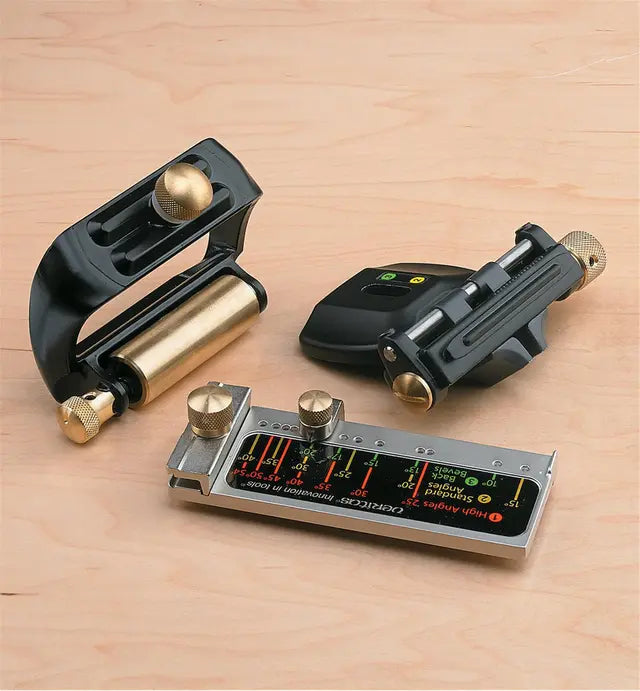 Woodworking honing guide set with brass and steel components on a light wood surface.