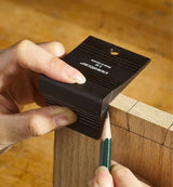 Hand using a woodworking marking gauge and pencil to mark lines on a wooden board