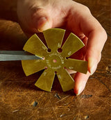 Hand holding brass bevel gauge for woodworking angle measurement on wood surface