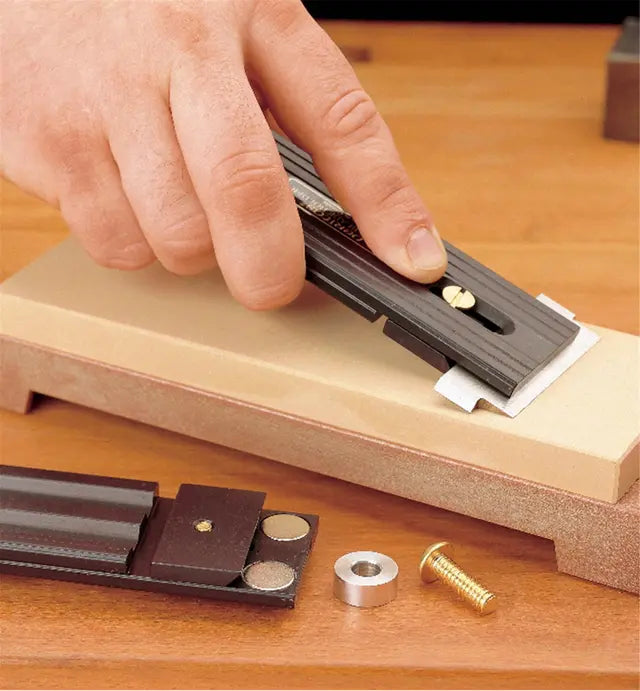 Hand sharpening woodworking chisel blade using honing guide on sharpening stone