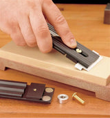 Hand sharpening woodworking chisel blade using honing guide on sharpening stone