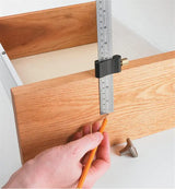 Person using a marking gauge ruler to measure and mark a precise line on a wooden drawer front.