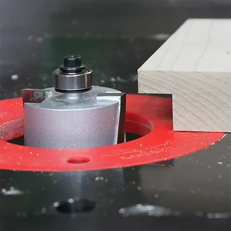 Close-up of a router bit cutting a dado groove in a wooden board on a router table