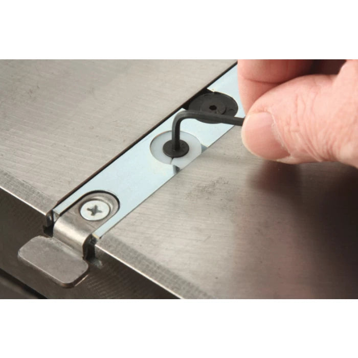 Hand adjusting metal miter bar with hex key on a woodworking table saw