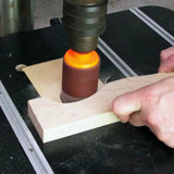 Oscillating spindle sander shaping a wooden board in a woodworking workshop.