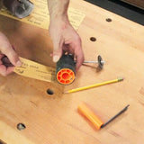 Hand assembling sanding drum with sandpaper on woodworking bench with pencil and tools visible