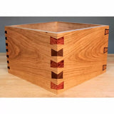Handcrafted wooden box with decorative dovetail joints on a workbench, woodworking project.