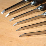 Set of sharp woodworking chisels with steel blades on a wooden workbench