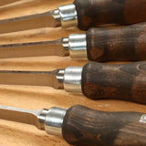 Set of woodworking chisels with steel blades and wooden handles on a wooden surface