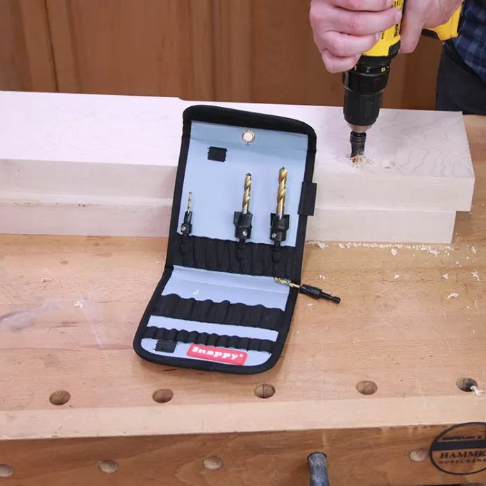 Woodworker using drill and countersink bit set on workbench with wood blocks