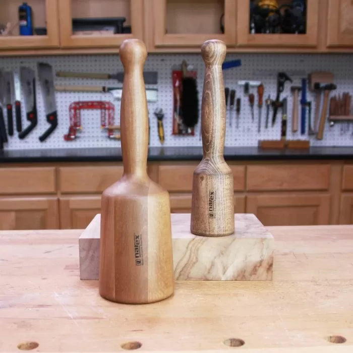 Two wooden mallets for woodworking on a workbench in a workshop with tools in the background