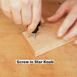 Hand screwing in star knob into wooden board on a woodworking workbench.