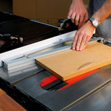 Woodworker cutting MDF board with table saw fence and push block in workshop setting