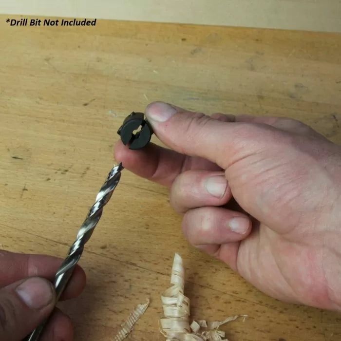 Hand holding drill bit stop collar above spiral drill bit on woodworking bench