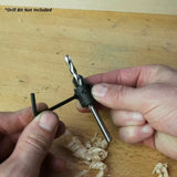Hands adjusting woodworking drill bit stop collar on workbench with wood shavings