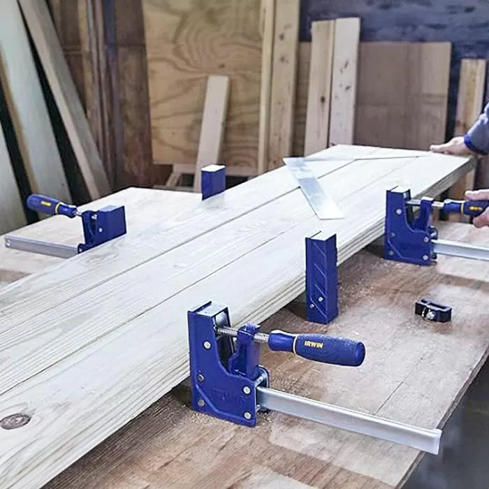 Parallel clamps securing wood boards on a workbench in a woodworking shop