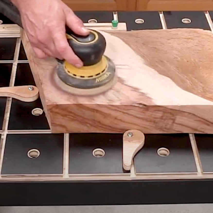 Hand sanding a wooden board with a power sander on a woodworking workbench