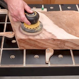 Hand sanding a wooden board with a power sander on a woodworking workbench