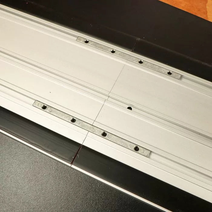 Aluminum track saw guide rail connector for woodworking, closeup view on workbench.