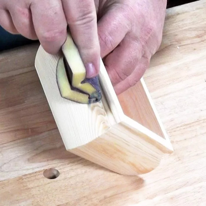 Hand sanding interior corner of a wooden box with a corner sanding block