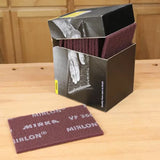 Box of Mirlon abrasive sanding pads with one pad displayed on a woodworking bench