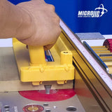 Hand guiding wood with yellow push block on router table for safe woodworking cuts