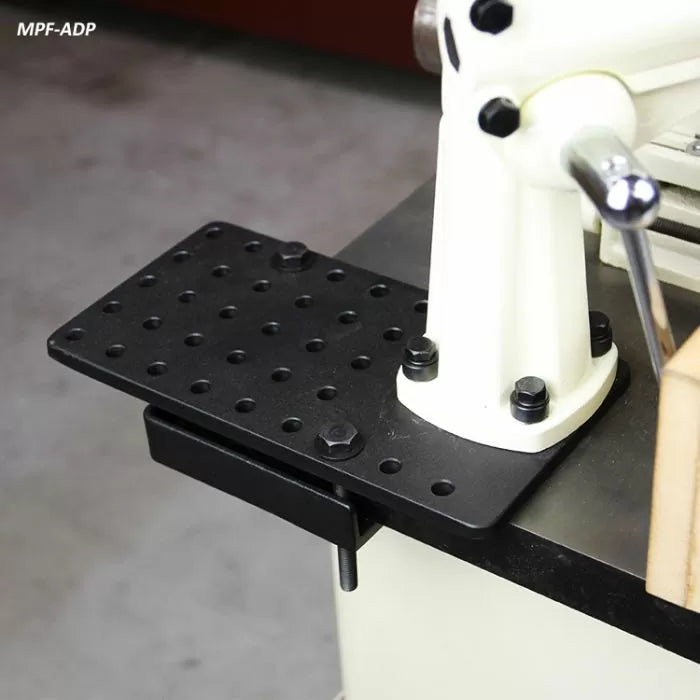 Drill press table attachment with black perforated metal plate mounted on woodworking machine