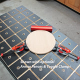 Woodworking workbench with grid holes, red clamps, round wood piece, and red fences
