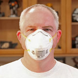 Man wearing N95 dust mask in woodworking shop for safety and respiratory protection