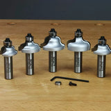 Ogee router bit set with five bits, hex key, bearing, and screw on a woodworking bench