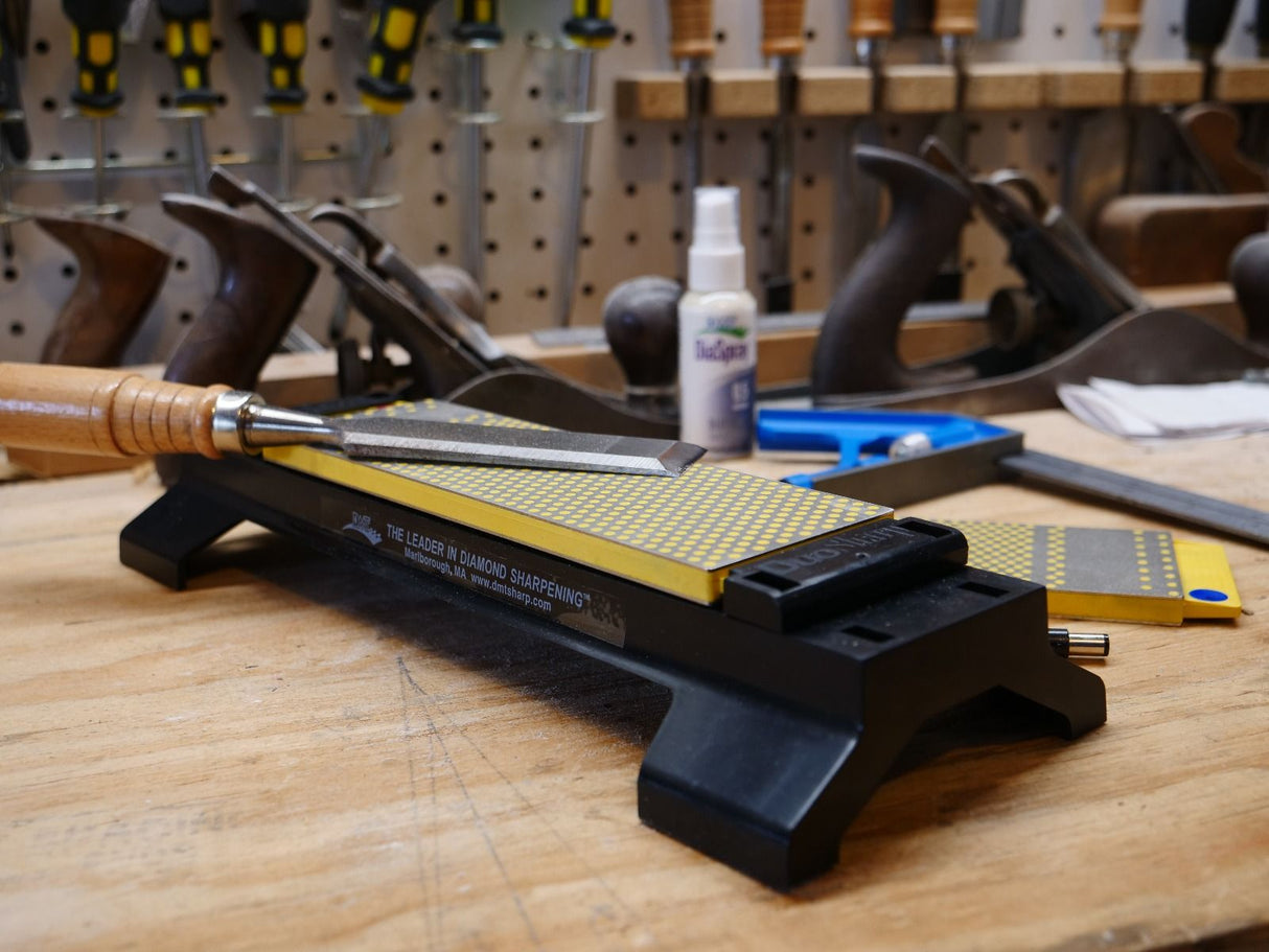 Diamond sharpening stone with woodworking chisel in workshop, hand tools in background