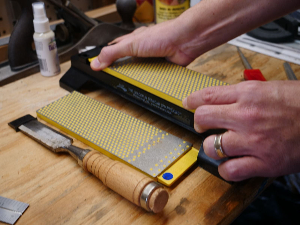 Sharpening a woodworking chisel on a diamond sharpening stone in a workshop