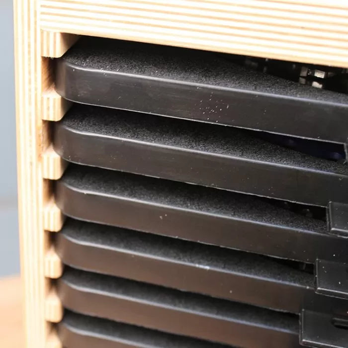 Close-up of black plastic trays stacked in a wooden organizer for woodworking tools.